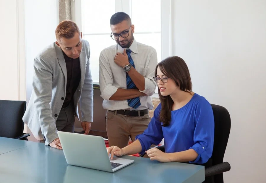 Three professionals reviewing laptop at office