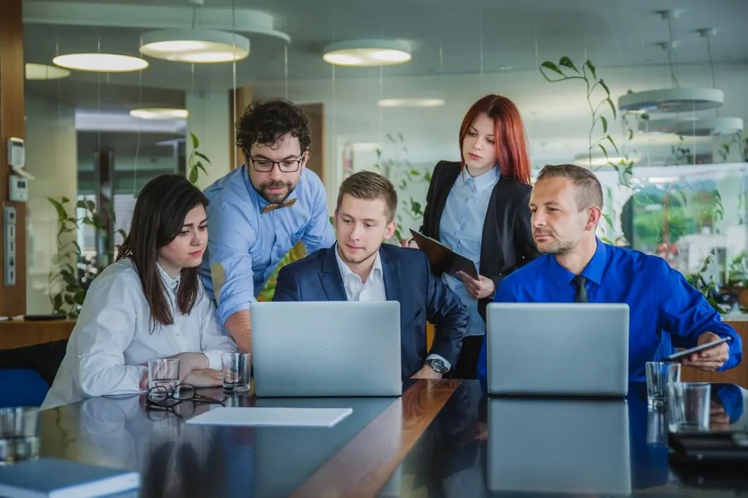 Business team collaborating around two laptops