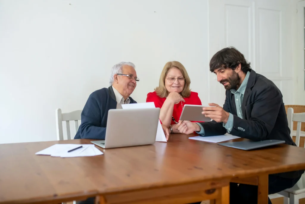 Business owners discussing marketing strategy with a Pearl Lemon Consulting expert, reviewing data on a tablet and laptop.